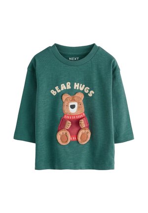 Camicia verde in cotone a maniche lunghe con una grafica di un orso e il testo "BEAR HUGS", maglione rosso e dettagli beige. Tessuto morbido e testurizzato.