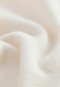 Weiches, weißes Fleecegewebe mit glatter Textur und sanftem Glanz, das gefaltete Schichten mit sanften Kurven und Tiefe zeigt.