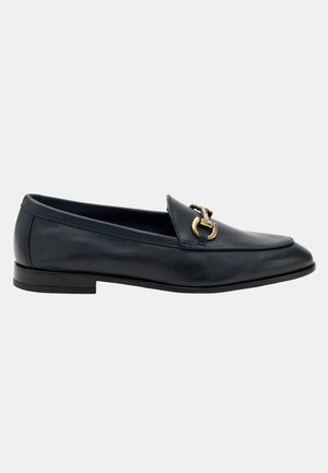 Mocasín de cuero negro con puntera redonda, que presenta un accesorio de hardware en tono dorado. Tacón bajo y plano con textura suave. Diseño simple y clásico.
