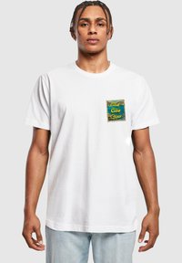 White cotton t-shirt featuring a blue and gold patch on the left chest with the text "Ciao Ciao Ciao." Short sleeves and relaxed fit.
