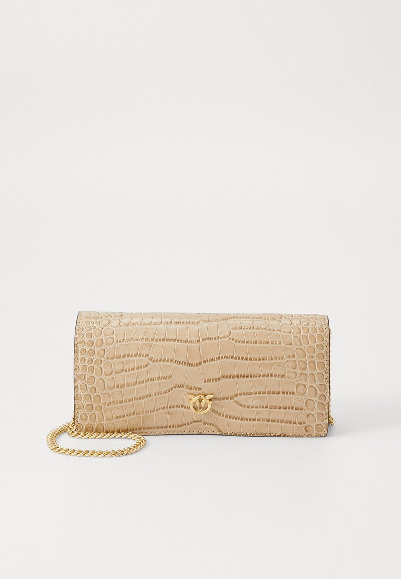 Kreminės spalvos dirbtinio krokodilo odos piniginė su auksiniu grandinės dirželiu. Atrodo tekstūruotas paviršius ir subtilus logotipo akcentas priekyje.