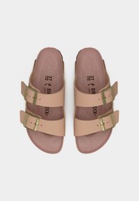 Ζευγάρι μπεζ σανδαλιών Birkenstock με δύο ρυθμιζόμενες λουρίδες και χρυσά αγκράφες, μέγεθος 37, σε λευκό φόντο.