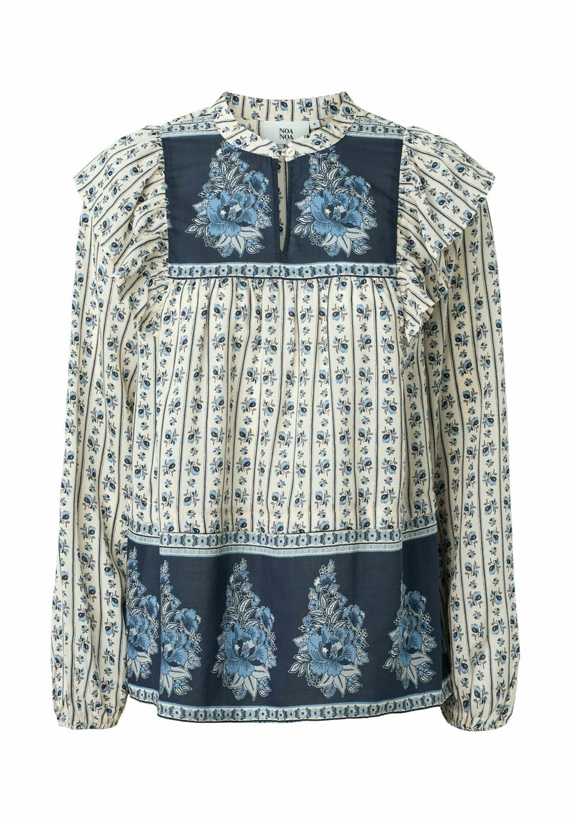 Blouse à manches longues avec motifs floraux bleus sur tissu crème, avec volants aux épaules et panneaux floraux bleu foncé contrastants à l'avant.