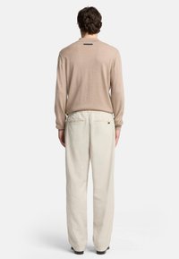 Beżowy sweter dzianinowy i jasnobeżowe spodnie z szerokimi nogawkami, z teksturowanym wykończeniem i dwoma tylnymi kieszeniami. Minimalistyczny design z detalem metki.