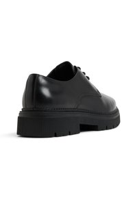 Mustat nahkakengät, joissa on pyöreä kärki, pyöristetty korko ja paksu kuvioitu musta kumipohja. Sisältää hienovaraisia ompeleita ja nauhakiinnityksen.