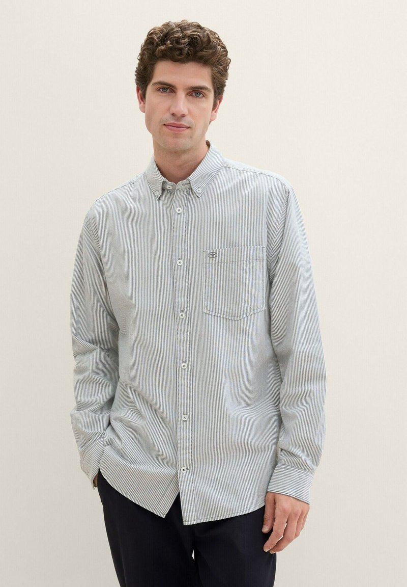 Camisa de botón a rayas azul y blanca con un bolsillo en el pecho, mangas largas y cuello. Tejido de mezcla de algodón con una textura suave.