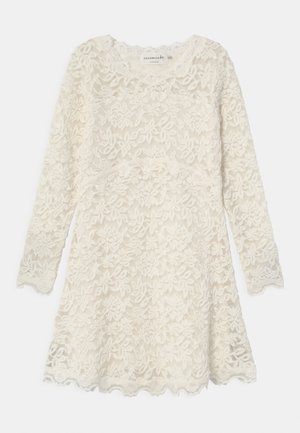 Weißes Spitzenkleid mit langen Ärmeln, floralem Muster, gewelltem Saum und rundem Ausschnitt. Semi-transparente Textur mit gestuften Details.