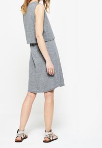 Robe grise en deux pièces fabriquée dans un tissu doux et texturé. Haut sans manches au design court, associé à une jupe longueur genou.