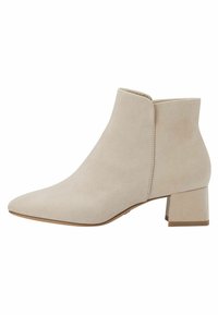Botín de ante beige con punta afilada y tacón bajo. Textura suave y diseño minimalista, con un corte lateral sin costuras.