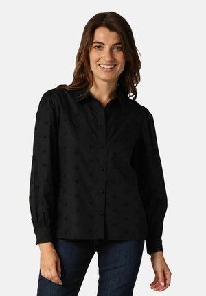 Chemise noire à boutons en tissu texturé avec de petits motifs en forme de cœurs en relief. Elle possède un col classique et des manches longues.