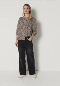 Light brown blouse with black leopard print, button-up design, 3/4 sleeves. Paired with high-waisted black jeans and white sneakers.