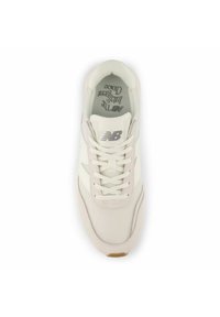 Sneaker atletico beige chiaro realizzato in materiali in rete e suede, con punta rotonda, design con lacci e texture morbida. Dettagliato con un logo.