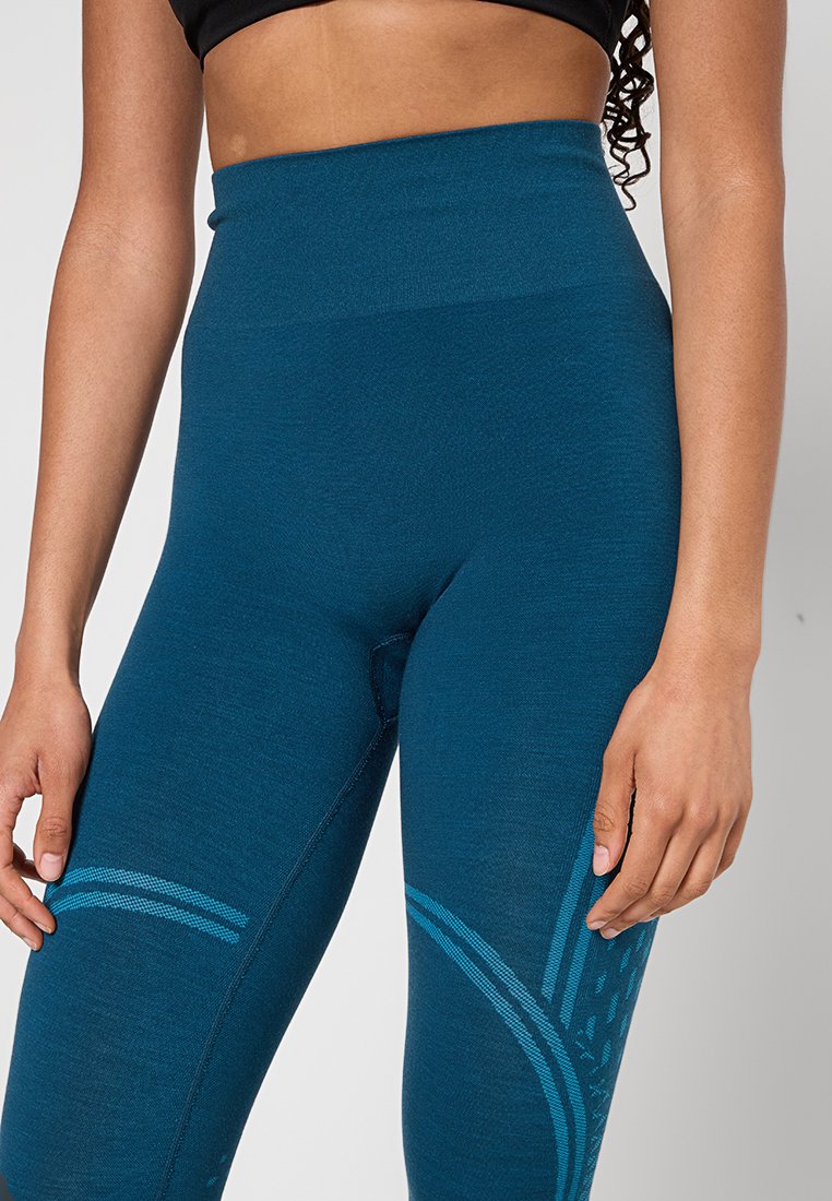 Tealowe legginsy z wysokim stanem, wykonane z teksturowanej tkaniny, z kontrastowymi niebieskimi wzorami po bokach i bezszwową konstrukcją.