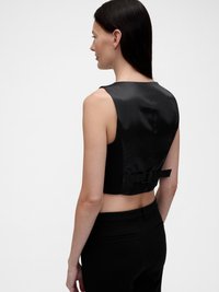 Μαύρο κομμένο τοπ από σατέν με κομψό σχέδιο, που διαθέτει φιόγκο στο πίσω μέρος και απαλή υφή. Συνδυάζεται με μαύρο παντελόνι.