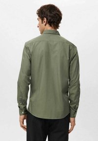 Langärmeliges Hemd in Olivgrün aus glattem Stoff, mit klassischem Kragen, Knopfmanschetten und abgerundetem Saum.