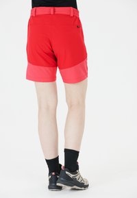 Röda shorts med en tvåfärgad design, som har en elastisk midja, en slät yta och ett kontrasterande, mörkare röd band i botten.
