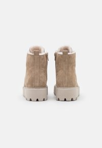 Bottines en suède beige avec doublure en fausse fourrure, fermeture éclair, et semelles en caoutchouc épais avec un motif de crampons.