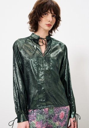 Glanzende groene blouse met een hoge kraag, een sleutelgatopening en een strikdetail. Lange mouwen hebben gathered manchetten. Glad, reflecterend textuur van de stof.