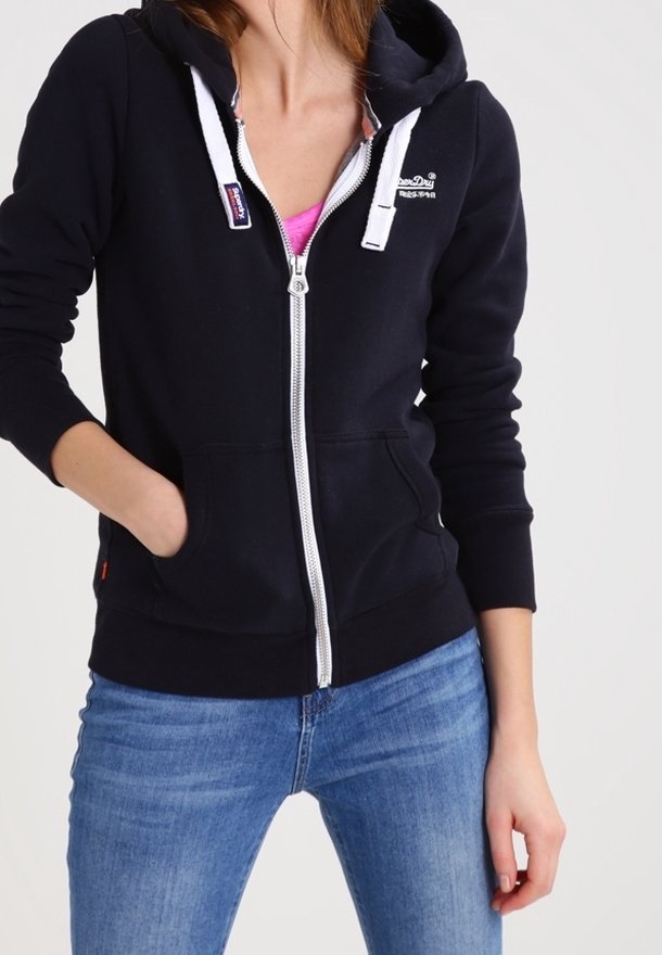 Marinblå zip-up huvtröja med en framlapp, vita snören och silverdragkedja. Har en logotyp på bröstet och ribbade ärmslut.