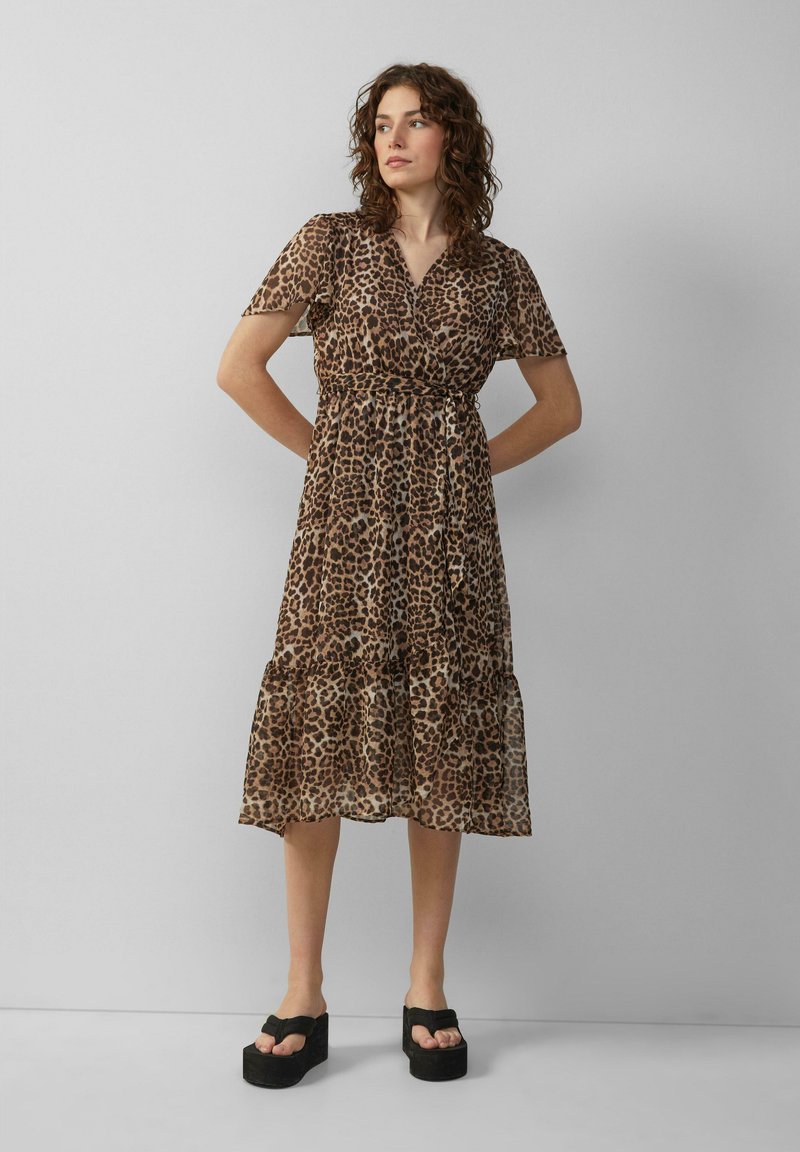 Jurkend met luipaardprint in doorschijnende stof, met korte mouwen, een wikkelontwerp, een gelaagde rok en een middellange snit. Zwarte plateau-sandalen maken de look compleet.