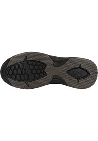 Schwarze Gummisohle mit strukturierten Oberflächen in hexagonalen und kreisförmigen Mustern. Markenlogo im Fersenbereich geprägt.