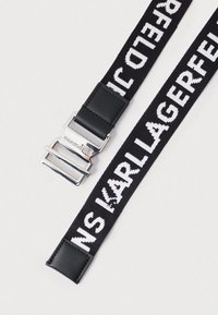 Cinto de tecido preto com texto branco "KARL LAGERFELD", extremidades em pele preta e fivela metálica prateada gravada com o nome da marca.