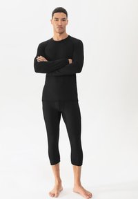 Schwarzes Langarmshirt und Leggings aus einem glatten, dehnbaren Material. Beide verfügen über taillierte Designs mit Rundhalsausschnitt und knöchellangem Saum.