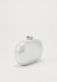 Mała srebrna torebka kopertówka o fakturowanej powierzchni, z zaokrąglonymi krawędziami i metalowym zapięciem u góry, na jednolitym jasnym tle.