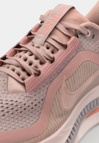Svijetlo ružičasti Nike Pegasus tenisice s mrežastim gornjim dijelom, teksturiranim naglascima i fleksibilnom potplatom. Zatvaranje na vezanje s perforacijama za ventilaciju.