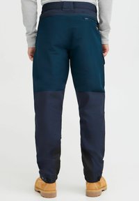 Navy blue waterproof pants with a contrasting darker blue lower section, adjustable cuffs, and a zippered pocket on the back.