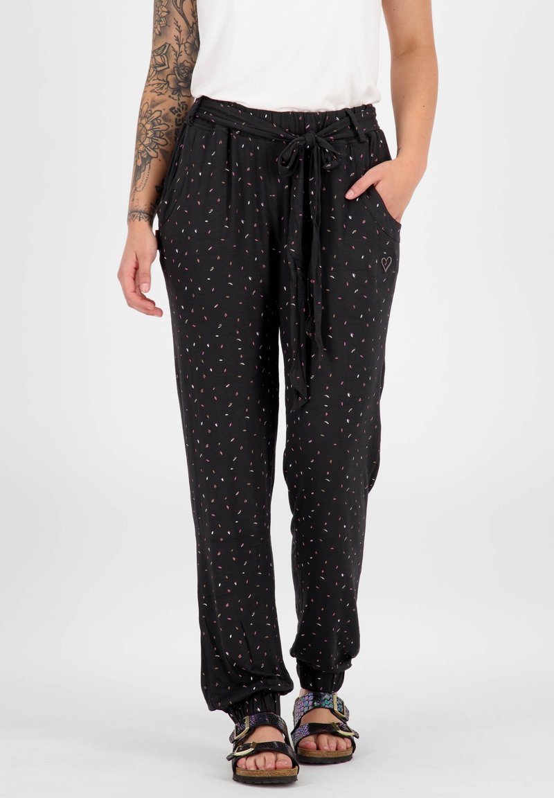 Černé vzorované kalhoty se stahovacími šňůrkami v pase, s tečkovanými vícebarevnými akcenty a bočními kapsami; nošeny s vzorovanými sandály.