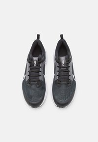 Scarpe sportive nere con tomaia in rete, chiusura con lacci e dettagli grigi. Presentano una suola bianca e una linguetta sul tallone per facilitarne l'indossamento.