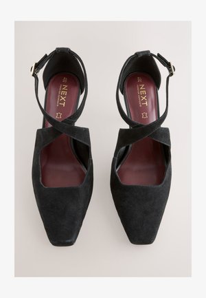 Mustad seemisnahast kõrged kontsakingad, nelinurkse ninaga, ristuvate rihmade disainiga ja peene pahkluu rihmaga, millel on kuldne pandla.