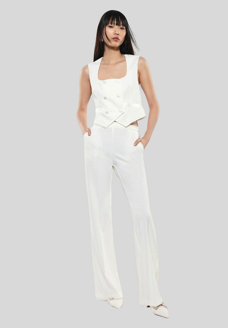 Gilet bianco su misura con scollatura quadrata e bottoni doppi, abbinato a pantaloni bianchi a gamba larga. Design liscio e minimalista.