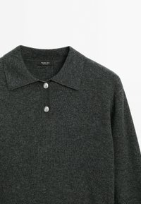 Polo en maille gris foncé à manches longues avec un col et deux boutons argentés au niveau de l'encolure.