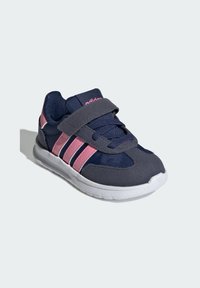 Mornarsko plava sportska cipela s ružičastim detaljima, s gornjim dijelom od tkanine, debelim potplatom i čičak trakama preko vezica za sigurno pristajanje.