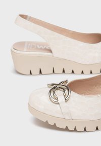 Zapatos slingback blancos con un patrón de cocodrilo texturizado, que presentan una hebilla de metal plateado y una suela de plataforma gruesa beige.