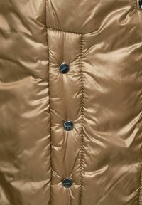 Brun uppblåsbar jacka med en slät textur, kviltad design och runda silverknappar framtill för stängning.