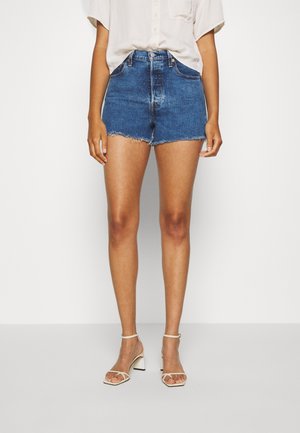 Denim shorts met rafelige zoom, hoge taille en zakken in een middelblauwe kleur. Geselecteerd met witte, bandjeshakken.