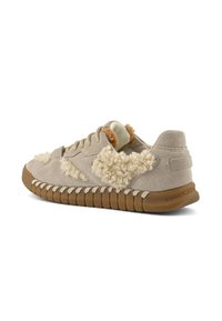 Beige Wildlederschuh mit flauschigen cremefarbenen Akzenten, einer braunen Gummisohle und einer strukturierten Außensohle mit erhobenen Rillen. Schnürsenkel in passender Farbe.