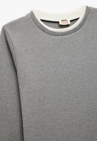 Felpa grigia a nido d'ape con colletto tondo beige. Presenta maniche lunghe e un tessuto testurizzato. Etichetta del marchio visibile all'interno del collo.