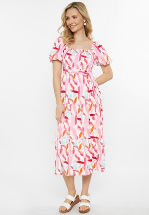 Maxime dress in pink fabric featuring a floral pattern with red, orange, and teal accents. Short puff sleeves and a fitted bodice with a layered skirt.