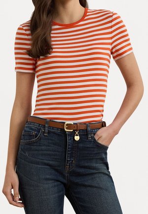 Camiseta de rayas rojas y blancas con mangas cortas y cuello redondo, combinada con jeans de color azul oscuro, que presenta un cinturón marrón con una hebilla dorada.