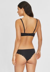 Schwarzes BH- und Slips-Set mit Spitzenbesatz, verstellbaren Trägern und glatter Stoffoberfläche, von hinten gesehen.