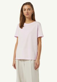 T-shirt rose clair à manches courtes en coton avec un col rond, arborant un logo subtil imprimé sur le devant. Silhouette à coupe droite.