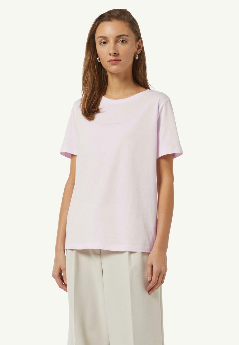 T-shirt rose clair à manches courtes en coton avec un col rond, arborant un logo subtil imprimé sur le devant. Silhouette à coupe droite.