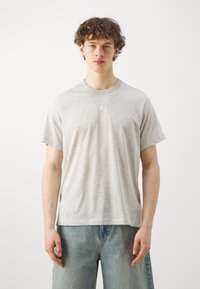 Gray cotton t-shirt with short sleeves, round neckline, and a small white logo on the chest. Worn with light blue denim shorts.
