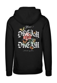 Sudadera negra con un diseño gráfico de flores y mariposas en la parte posterior, con texto blanco que dice "Tu SUEÑO no es mi SUEÑO, estoy haciendo lo mío."