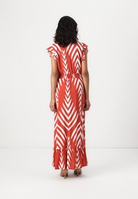 Maxime dress in red with white zigzag patterns, short ruffled sleeves, cinched waist, and flared hem. Smooth fabric with a soft texture.