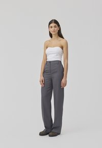Pantalons gris taille haute avec une coupe droite, associés à un top blanc sans bretelles. Le tissu semble lisse avec une coupe ajustée.